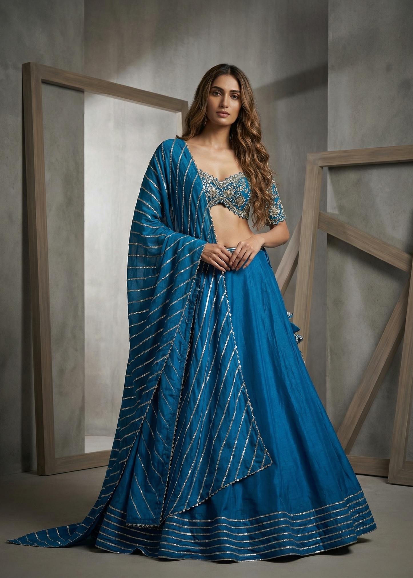 Woman in a blue saree with silver detailing standing against a neutral background