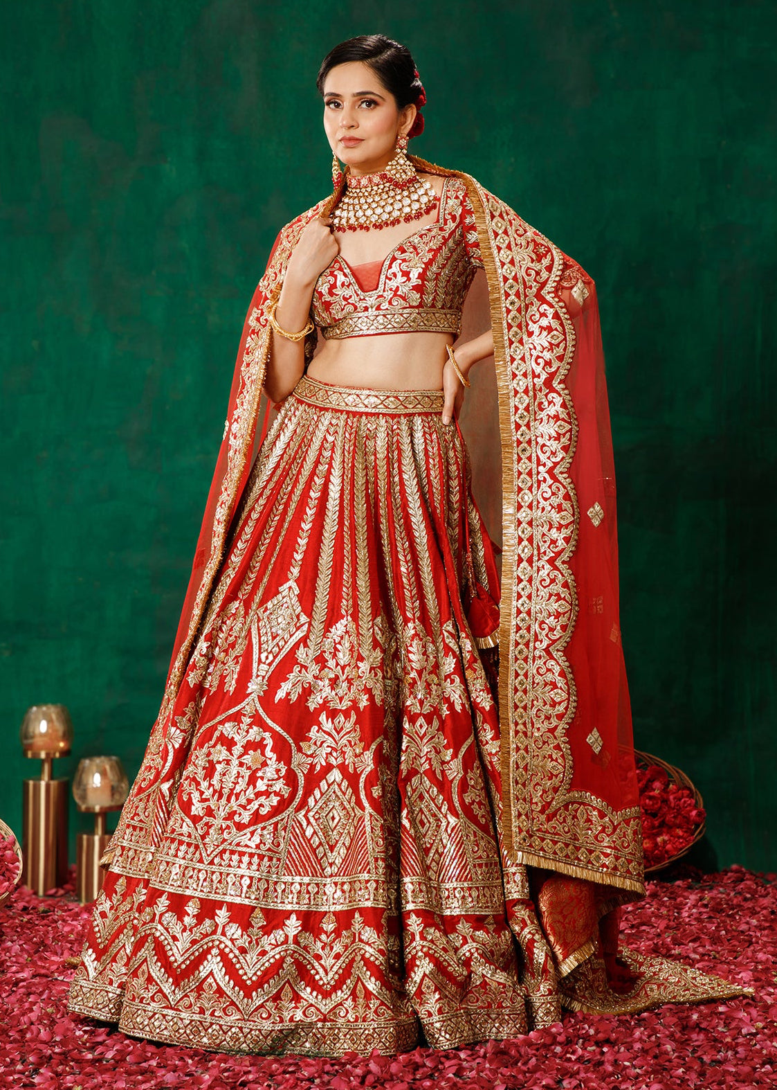 Woman in a red and gold embroidered traditional outfit on a green background