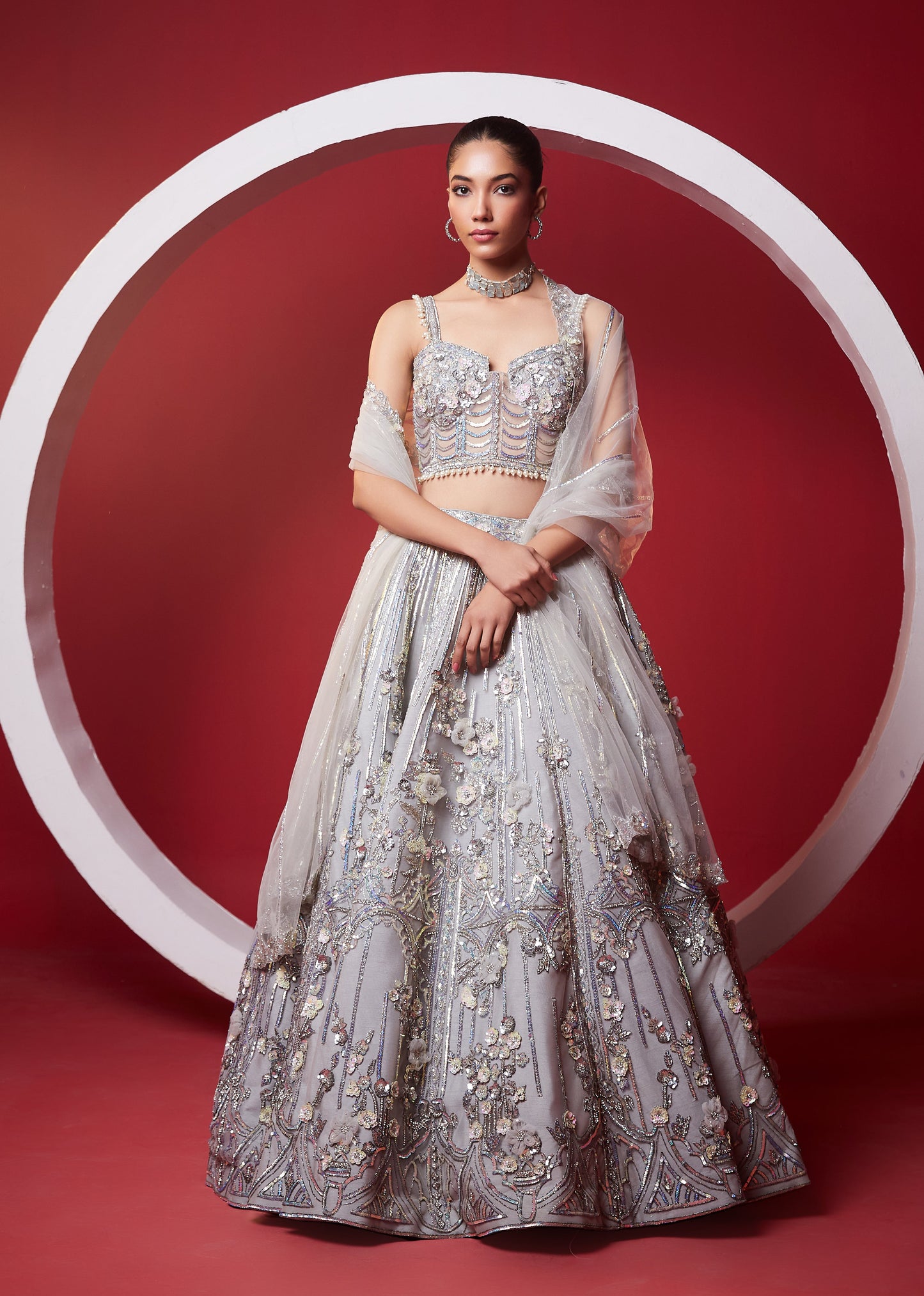 Woman in an elegant silver traditional outfit with a red background