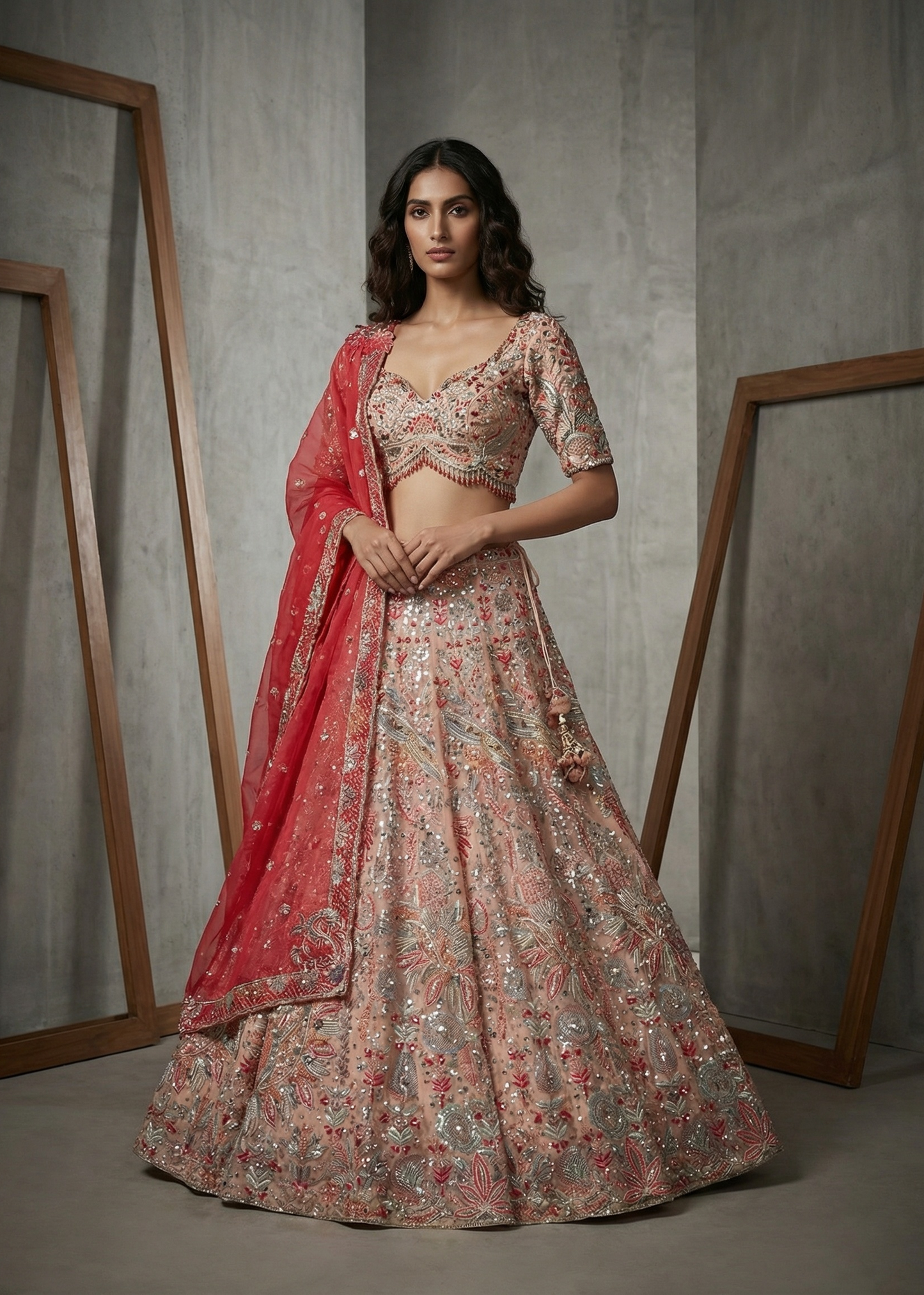 Woman wearing a floral lehenga with a red dupatta against a neutral background