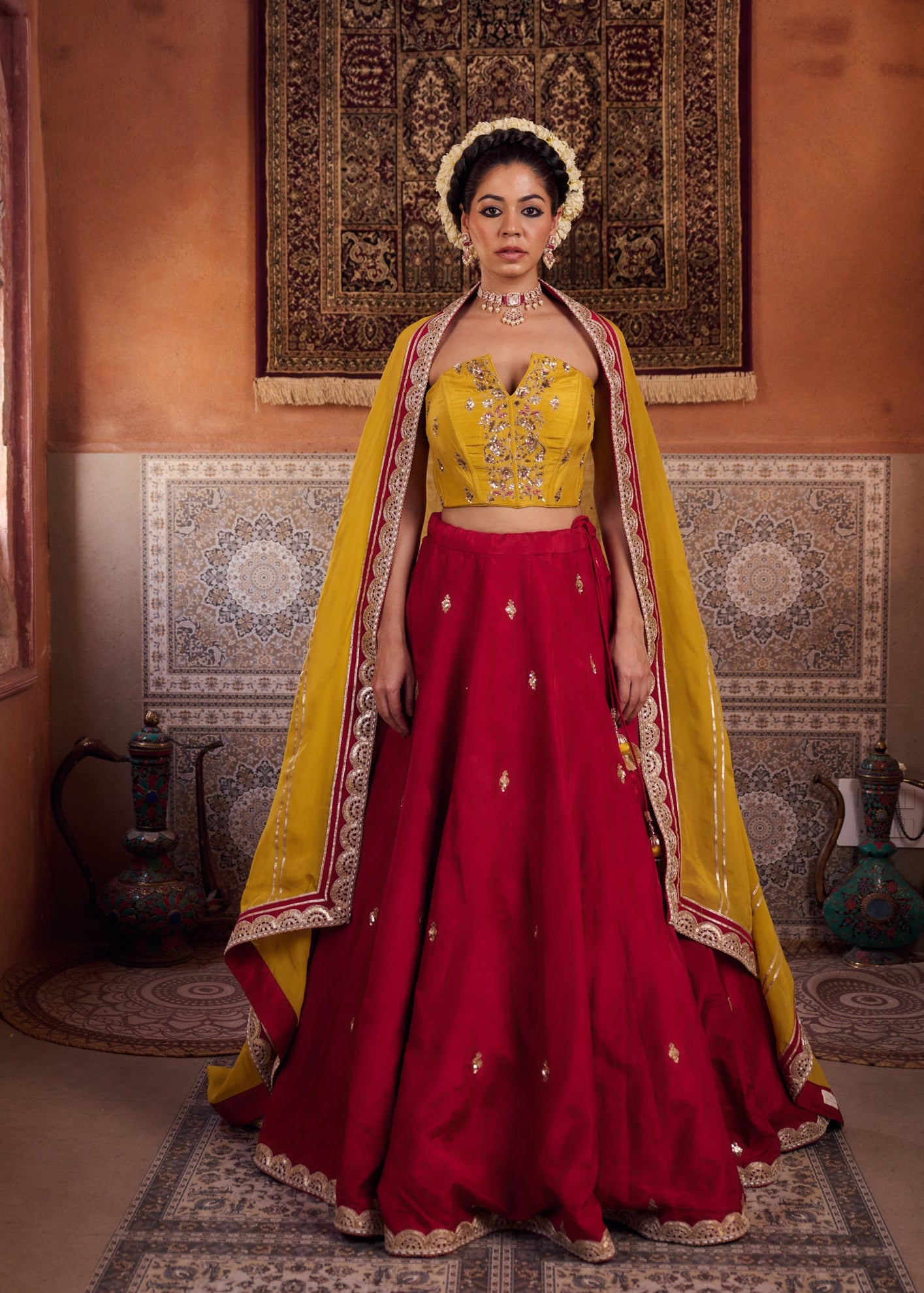 Woman in a red and yellow traditional outfit standing in a decorated room.