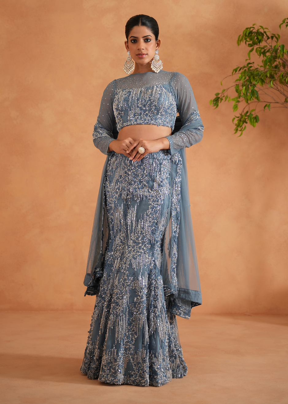 Woman wearing a blue patterned outfit against a beige background