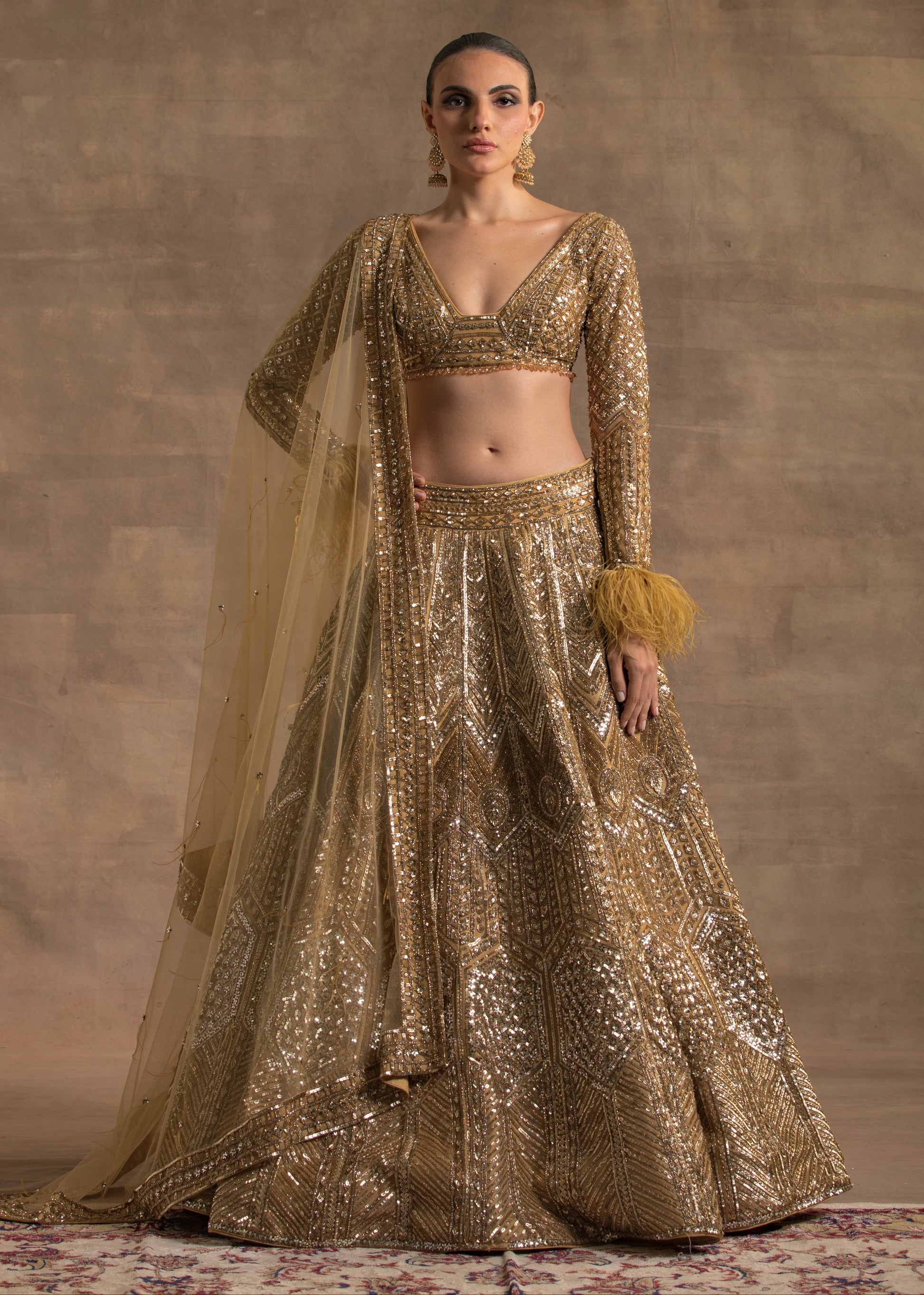 Woman wearing a gold traditional outfit with a plain background