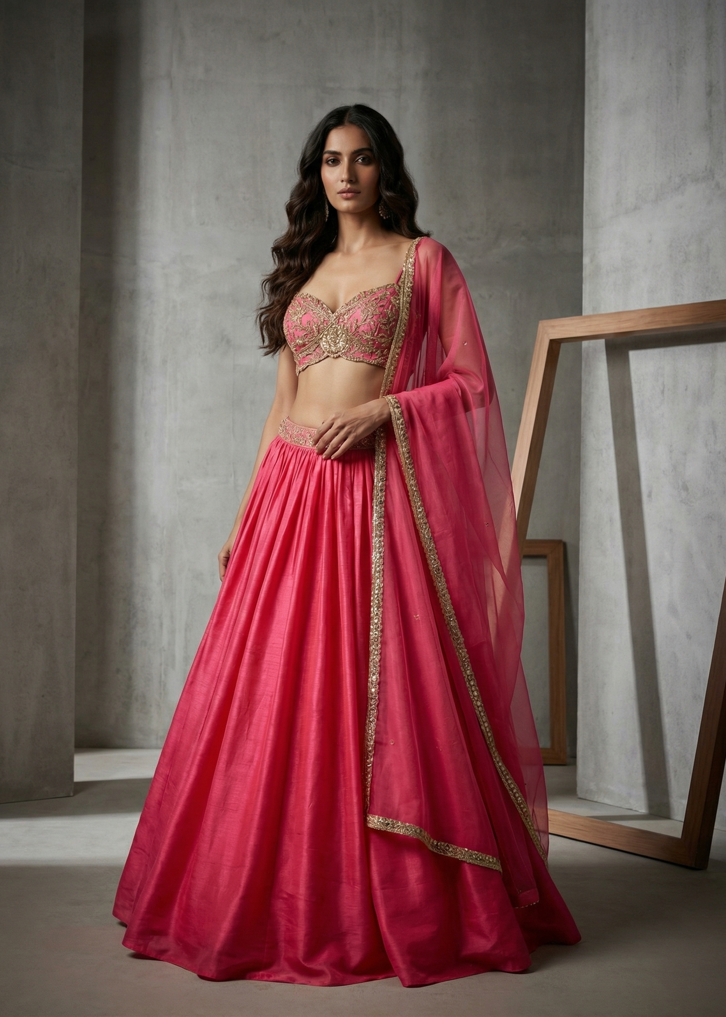 Woman in a pink traditional outfit standing against a gray wall.
