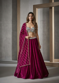 Woman wearing a magenta traditional outfit with intricate designs in a neutral setting