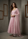 Woman in a pink traditional outfit with a matching dupatta against a neutral background