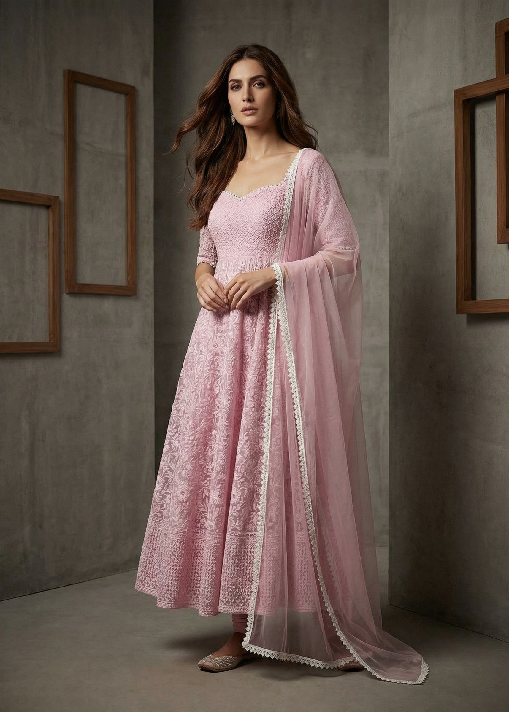 Woman in a pink traditional outfit with a matching dupatta against a neutral background