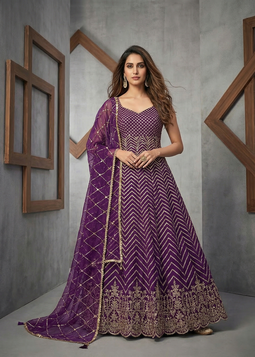 Woman wearing a purple embroidered traditional outfit against a gray background