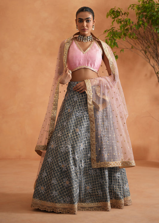 Woman in traditional outfit with pink blouse and patterned skirt against a beige background