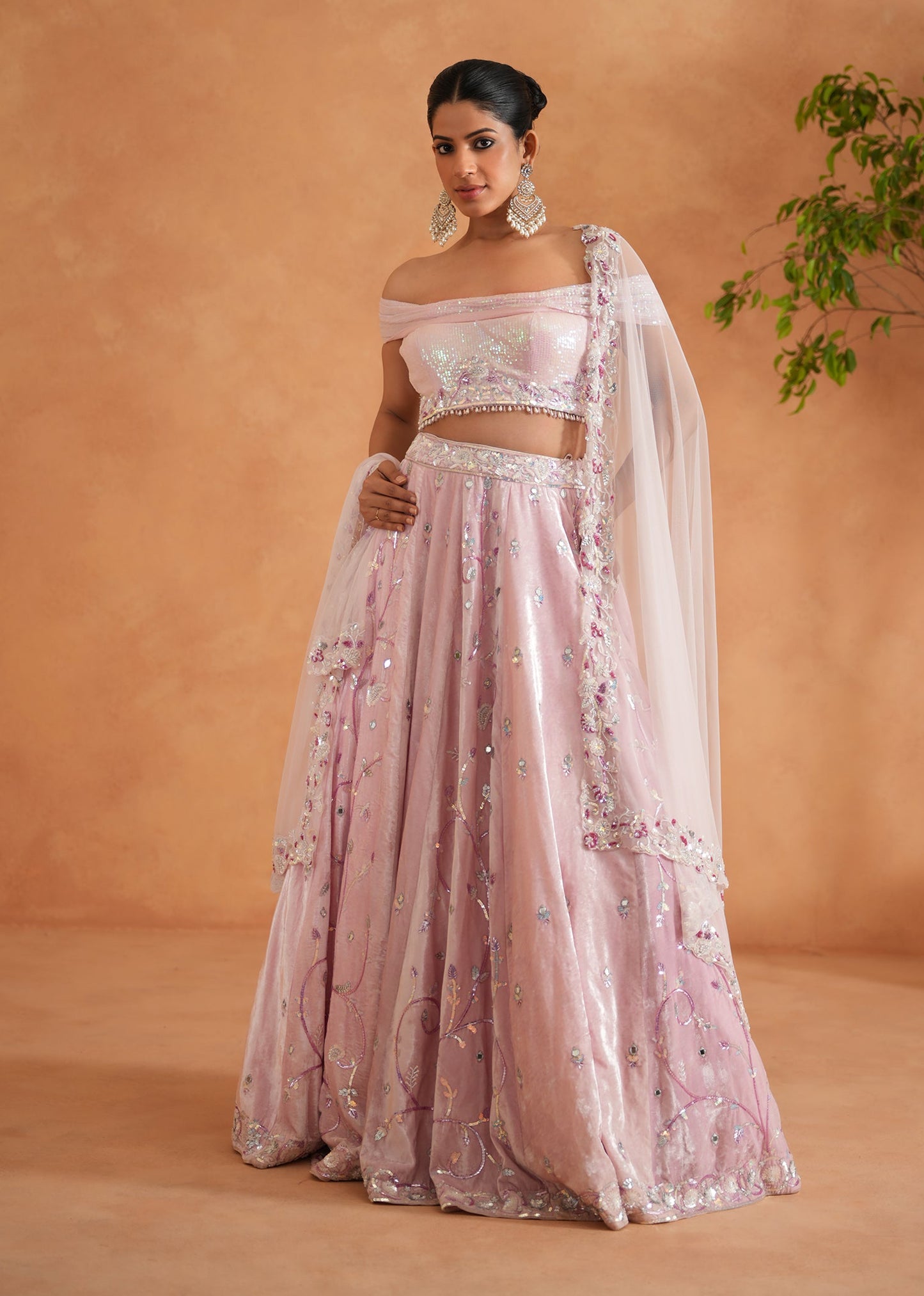 Woman in a pink embroidered traditional outfit against a beige background