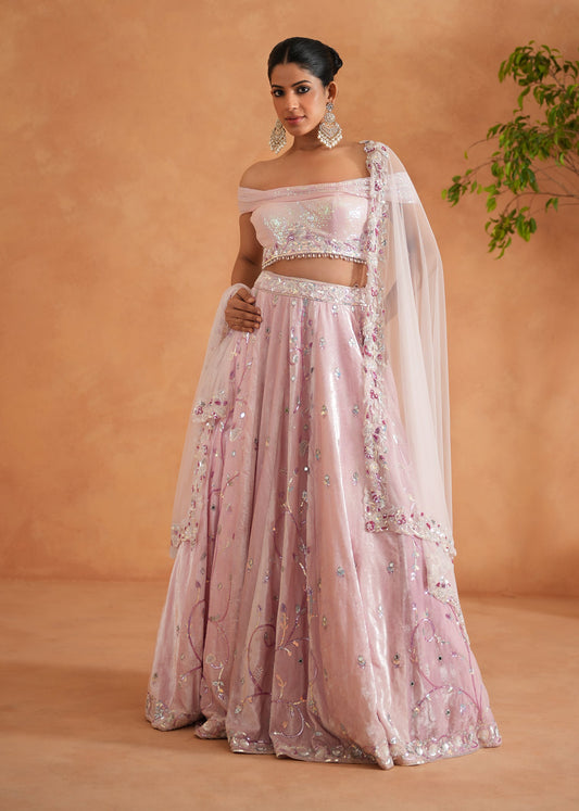 Woman in a pink embroidered traditional outfit against a beige background