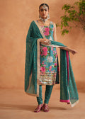 Woman in traditional outfit with floral design and green dupatta against a beige background