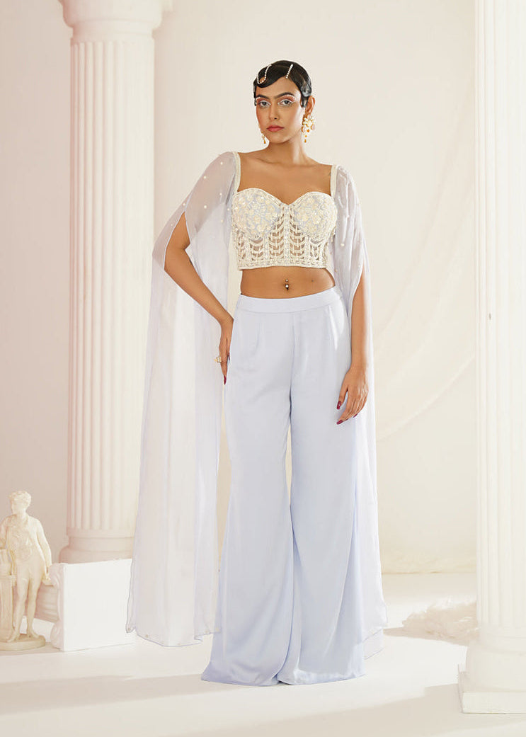 Woman in a white outfit standing in a classical setting with columns.