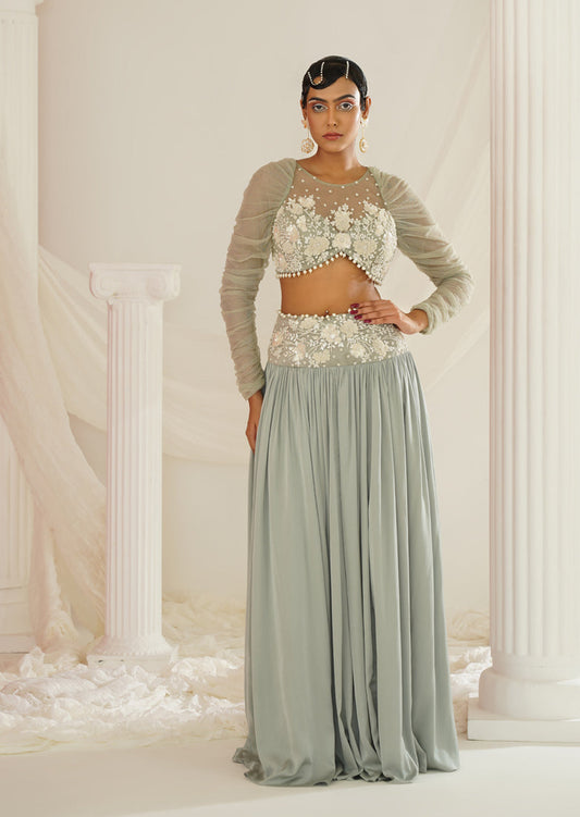 Woman in a floral top and long skirt standing in a classical setting with columns.