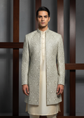 Man wearing a traditional embroidered sherwani against a neutral background