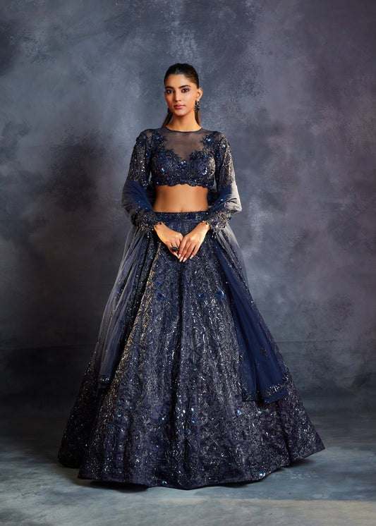 Woman wearing a dark blue embroidered outfit against a gray background