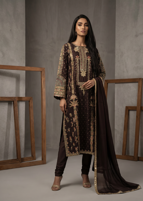 Woman wearing a dark brown embroidered outfit with a plain background