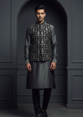 Man wearing a traditional embroidered outfit against a dark background
