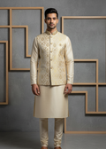 Man wearing a cream-colored traditional outfit with intricate patterns against a gray background