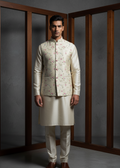 Man wearing a traditional cream-colored kurta with a floral patterned jacket against a gray background.