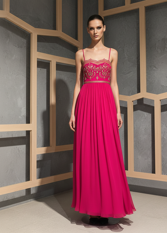 Woman wearing a pink evening gown with intricate detailing against a geometric wall.