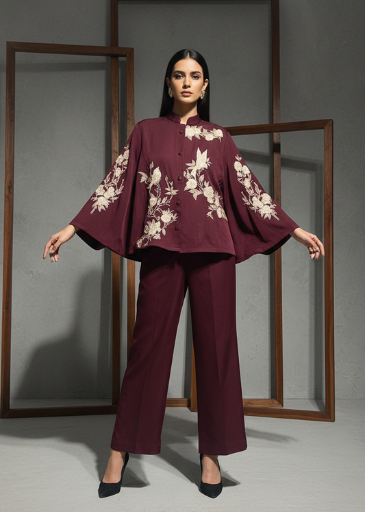 Woman wearing a burgundy outfit with floral embroidery against a gray background