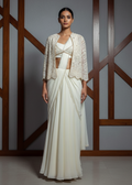 Woman wearing a white outfit with a textured top against a wooden lattice background