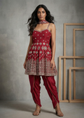 Woman wearing a red traditional outfit with intricate patterns against a gray background