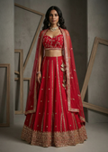 Woman wearing a red embroidered traditional outfit with gold details against a neutral background