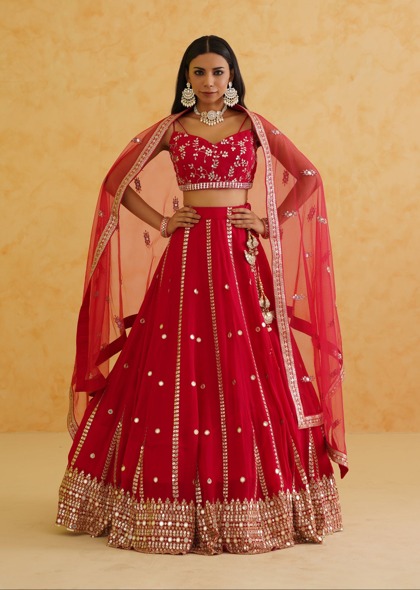 Woman wearing a red traditional outfit with gold details against a beige background