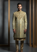 Man wearing a traditional embroidered sherwani against a dark background