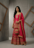 Woman in a traditional pink and gold outfit with jewelry against a gray background