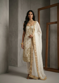 Woman wearing a traditional outfit with gold and white patterns against a neutral background
