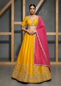 Woman wearing a yellow and pink traditional outfit with a wooden and gray background