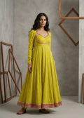 Woman wearing a yellow dress with pink accents in a minimalistic setting