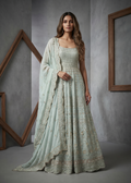 Woman wearing a light green traditional outfit with a matching dupatta in a gray studio setting.