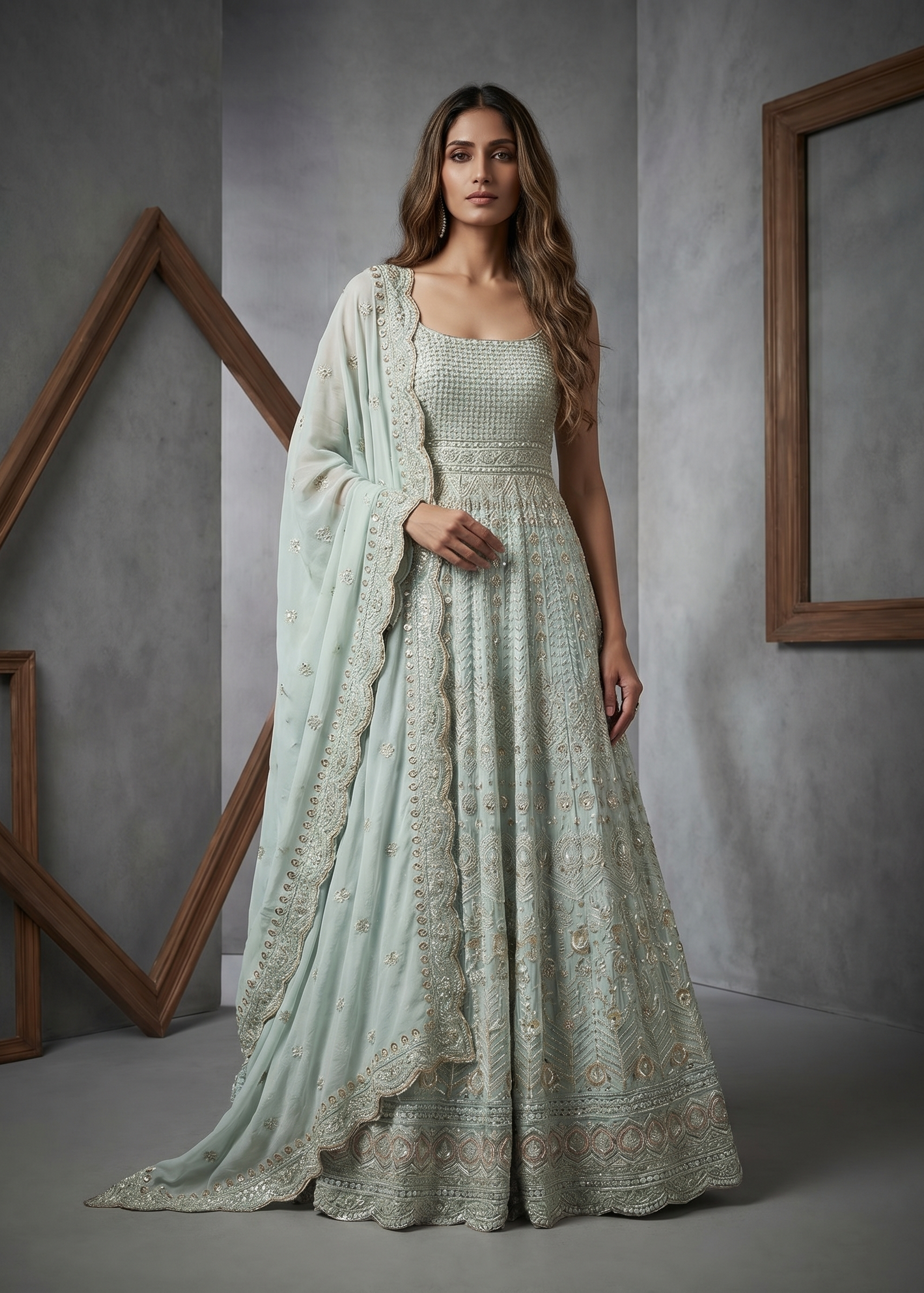 Woman wearing a light green traditional outfit with a matching dupatta in a gray studio setting.