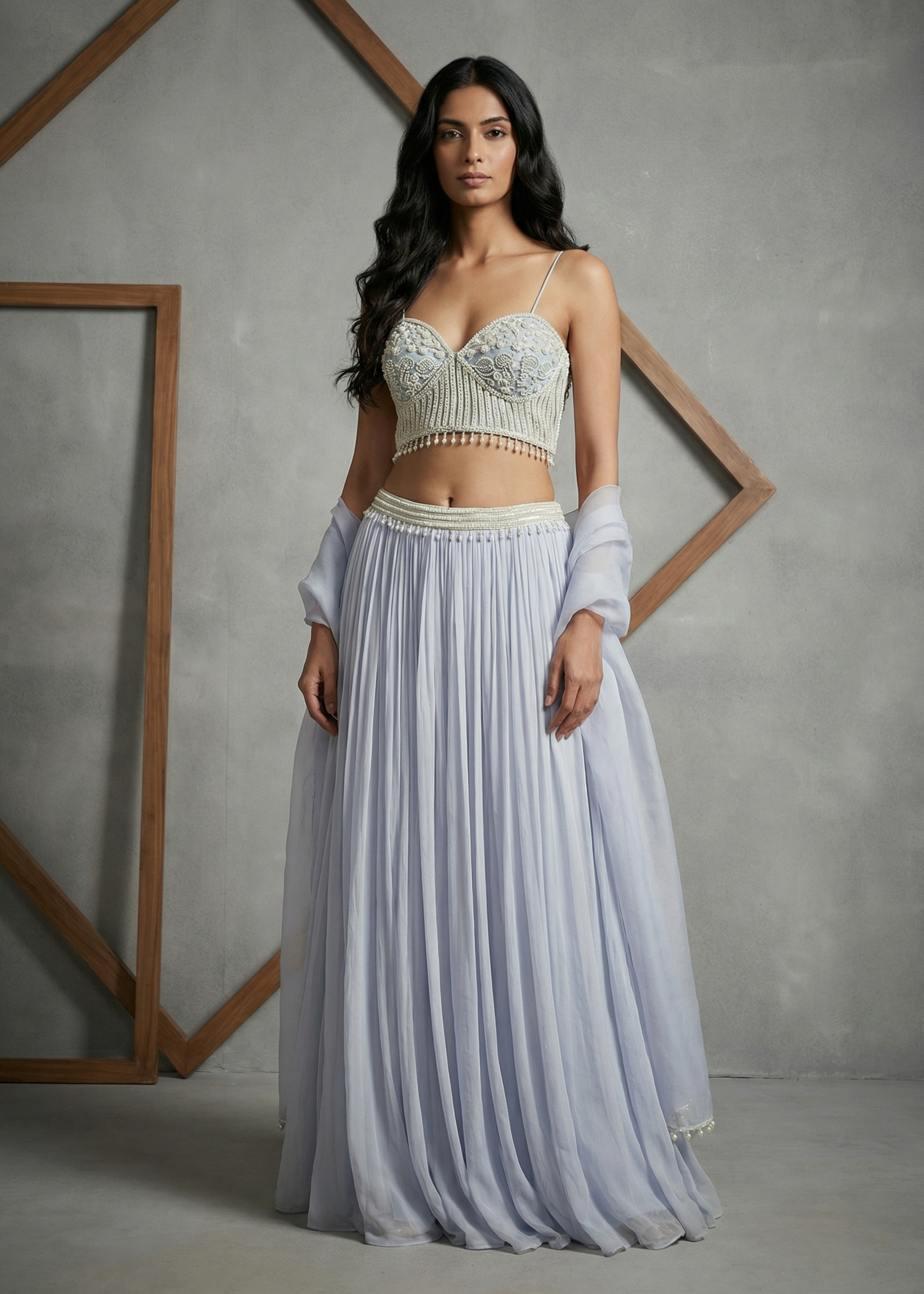 Woman wearing a light-colored top and flowing skirt against a gray background