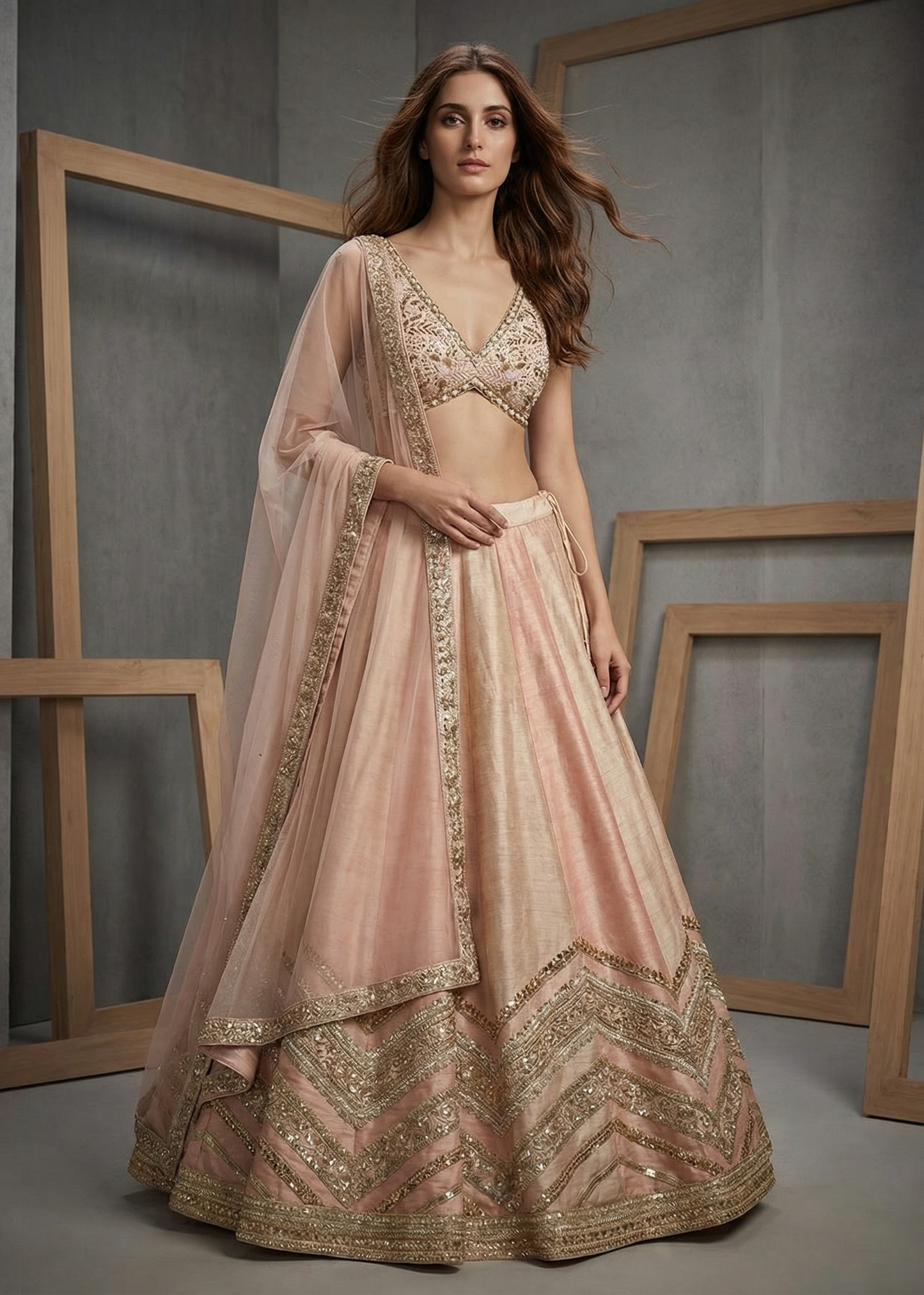 Woman wearing a traditional pink and gold embroidered outfit against a gray background with wooden frames.