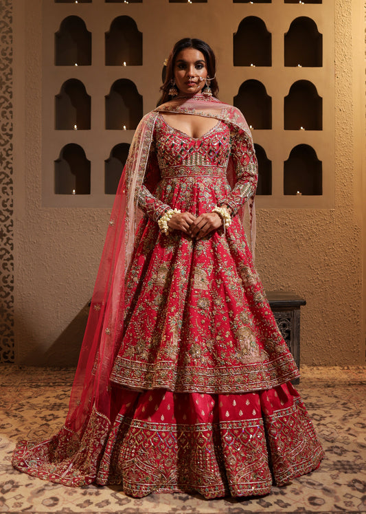 Woman in a red and gold traditional outfit standing against an ornate wall.