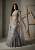 Woman in a silver beaded gown with a cape against a neutral background