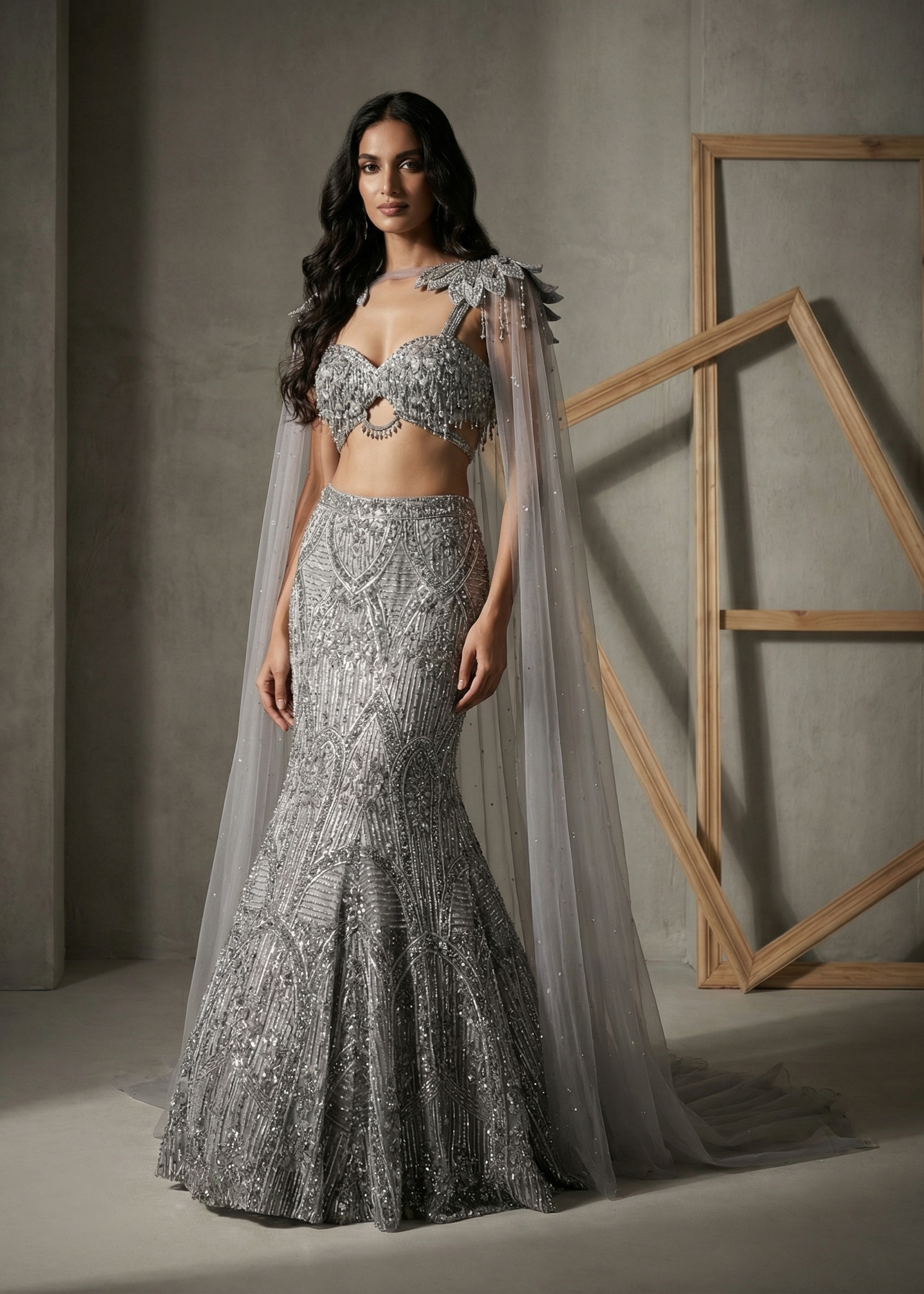 Woman in a silver beaded gown with a cape against a neutral background