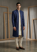 Man wearing a blue kurta with white pants in a minimalistic setting