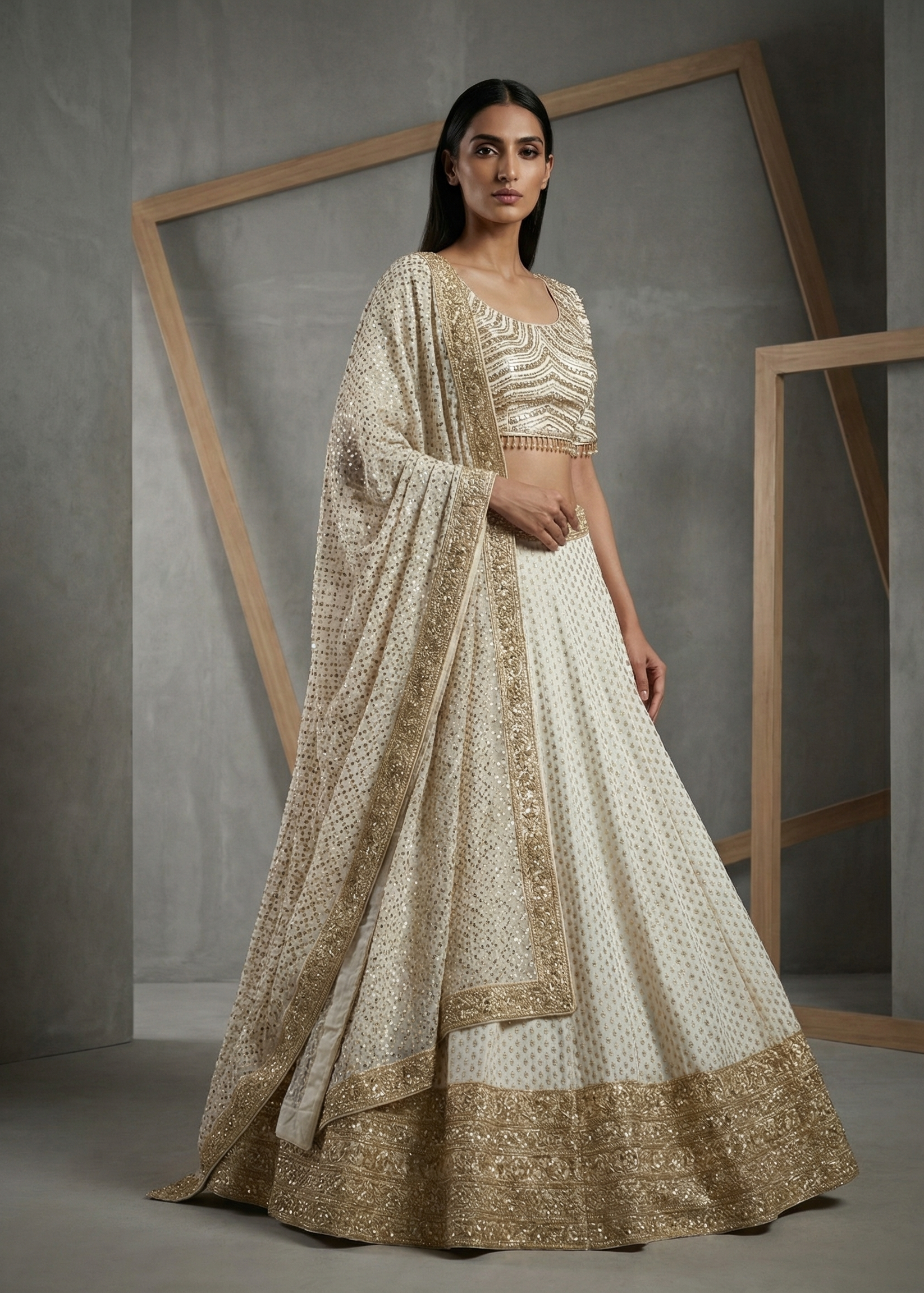 Woman wearing a traditional outfit with gold and white patterns against a gray background