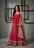 Woman wearing a red and gold traditional outfit with a matching dupatta against a gray background