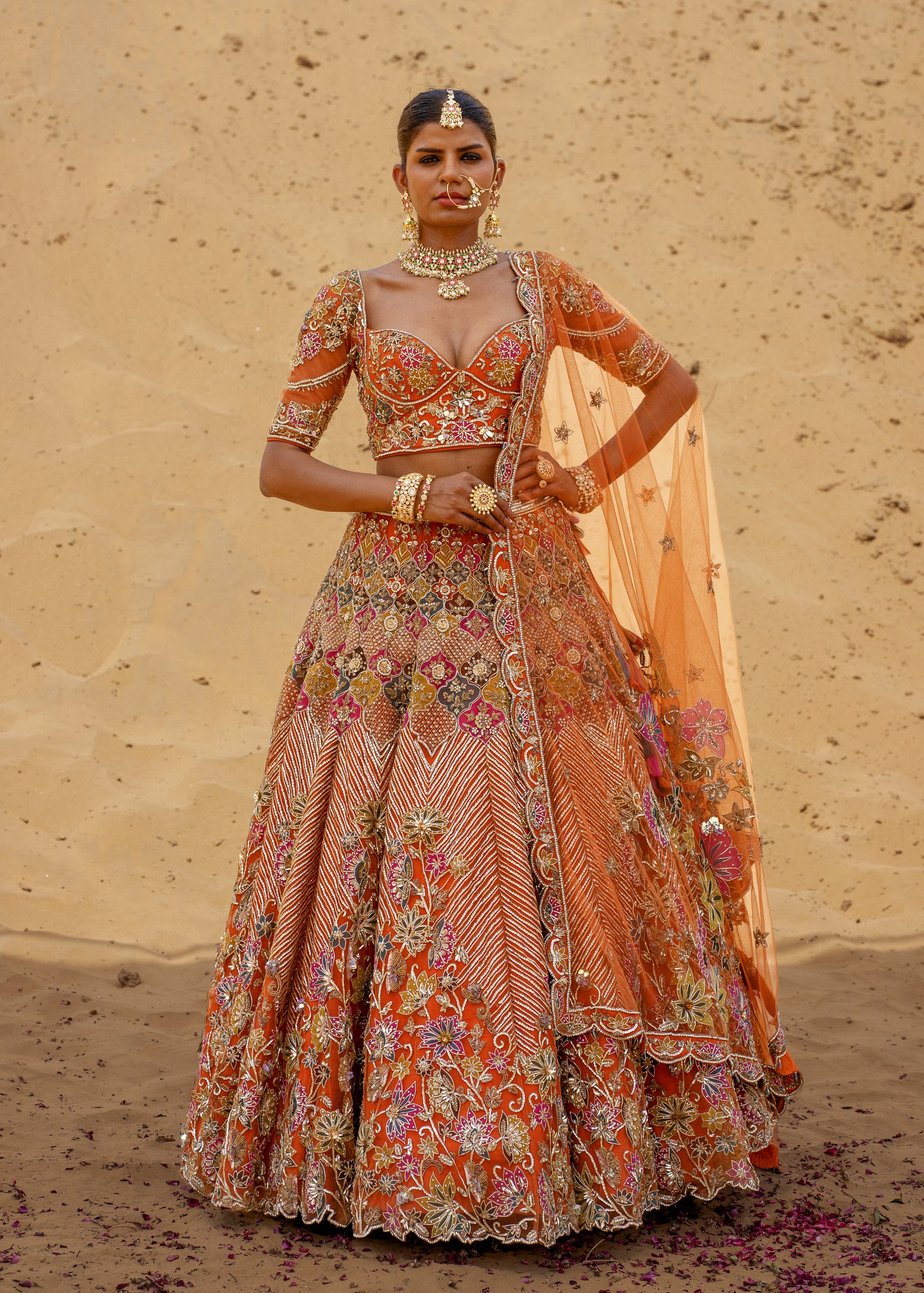 Woman in a traditional outfit with intricate patterns against a desert background