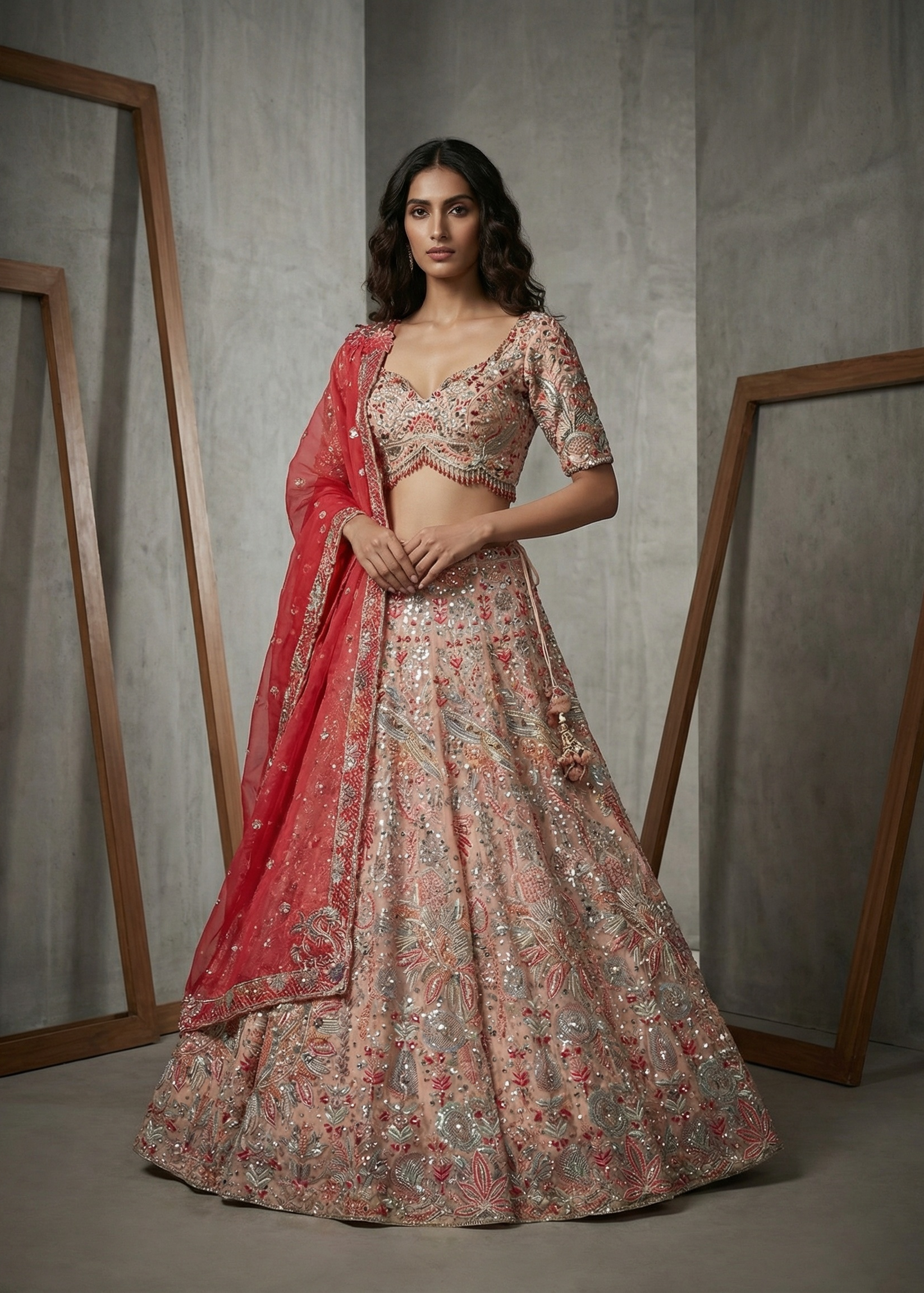 Woman wearing a floral lehenga with a red dupatta against a neutral background