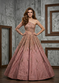 Woman wearing a pink evening gown with gold detailing in a room with gray walls and wooden frames.