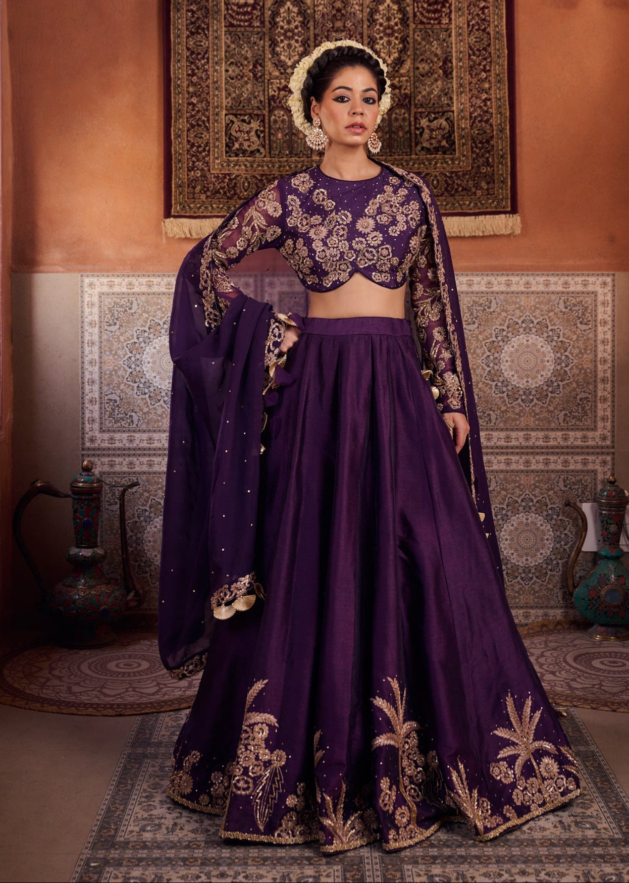 Woman in a traditional purple outfit with gold embroidery in an ornate room.