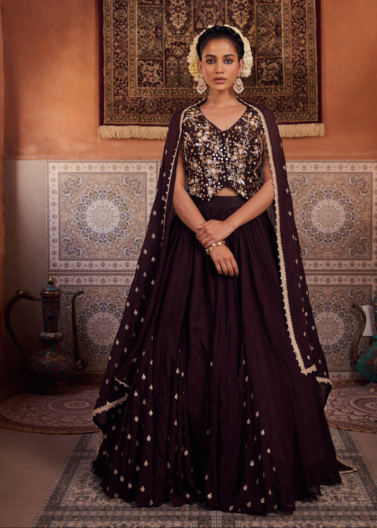 Woman in a dark purple traditional outfit with gold details in an ornate room.